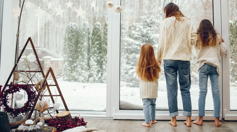 Mother with children. Family at home. People standing near winter windows