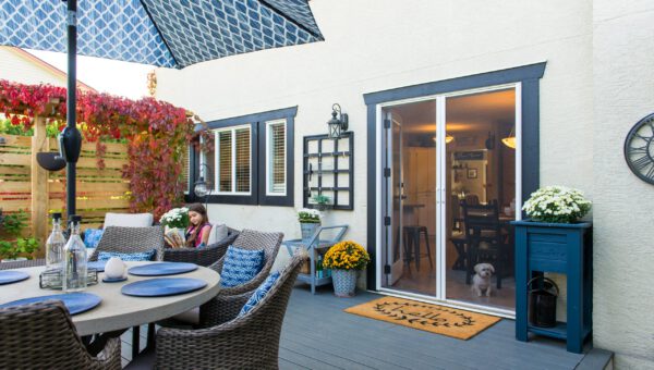 Family home patio with table, girl reading in chair and dog sitting in front of retractable double door screens
