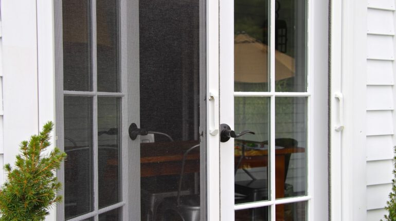 Close up shot of white wooden French doors with Phantom retractable screens