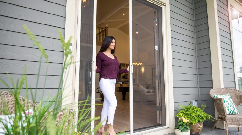 Woman stepping out of home between disappearing door screens