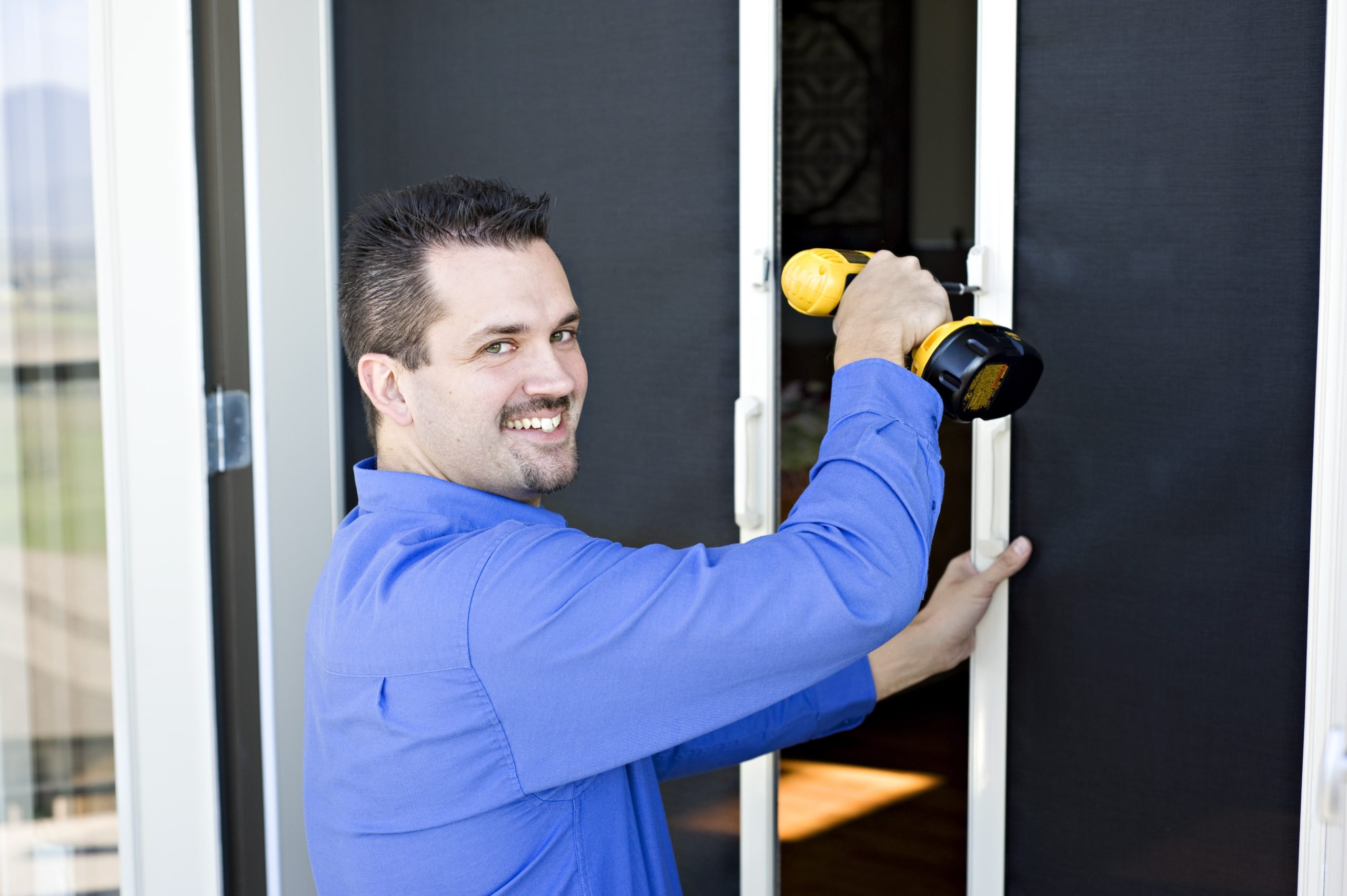 Man in blue installation retractable screen to door